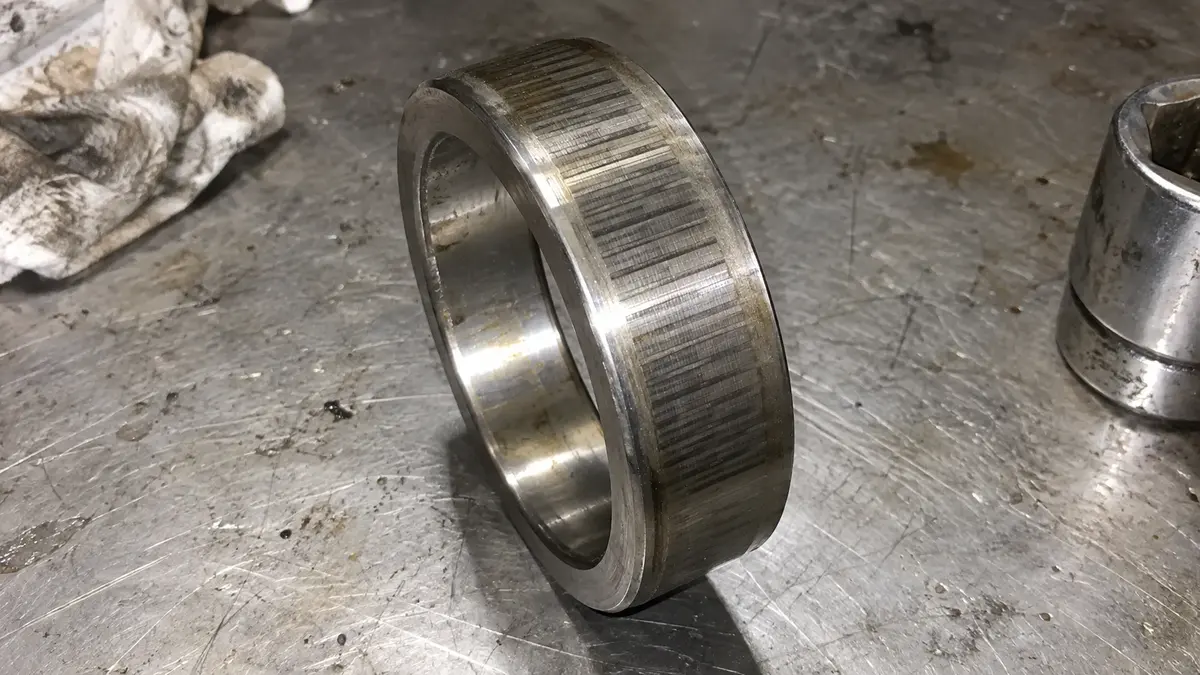 Electrical fluting on a cylindrical bearing inner ring: regular dark bars crossing the raceway parallel to the bearing axis, the discharge damage a hybrid ceramic bearing raises the resistance against but does not remove