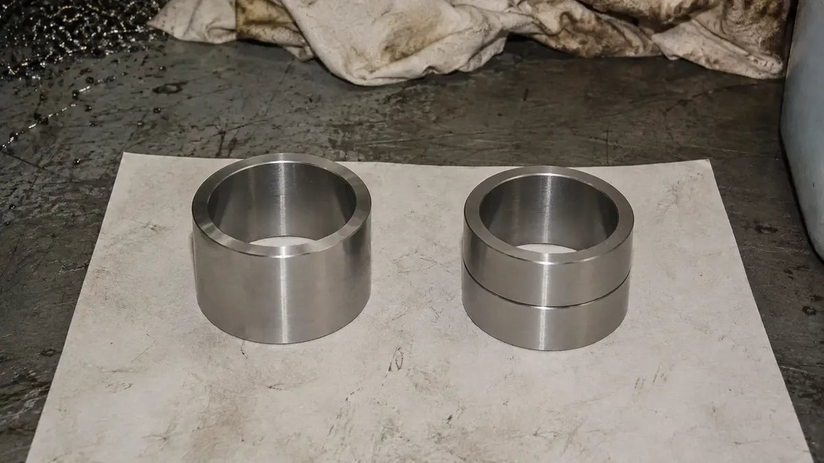 Dua bentuk cincin dalam untuk bearing rol silindris empat baris yang diletakkan berdampingan di meja inspeksi: cincin satu bagian tanpa flens di sebelah kiri, dan di sebelah kanan sepasang cincin dalam dengan lebar total yang sama, dengan sambungan tumpul yang memungkinkan desain FCD dipasang pada roll neck yang lebih besar