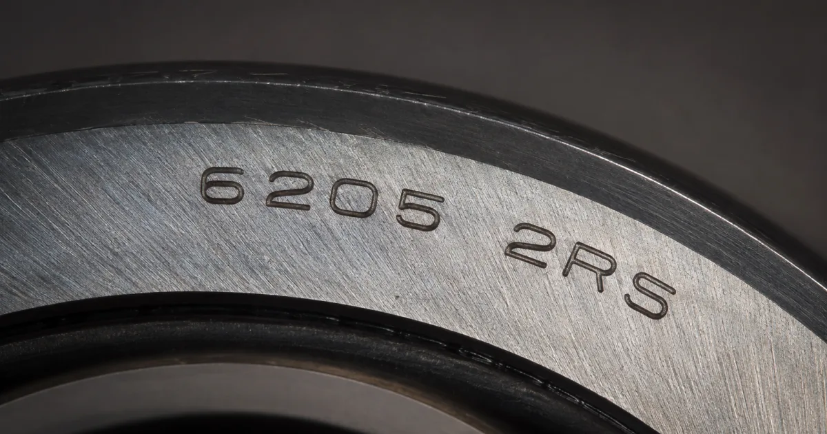 Macro close-up of a deep groove ball bearing ring laser-etched with the designation number 6205 2RS